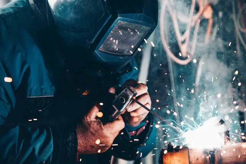 Welder working intensely, sparks flying, demonstrating high-capacity solutions for smooth, efficient production.