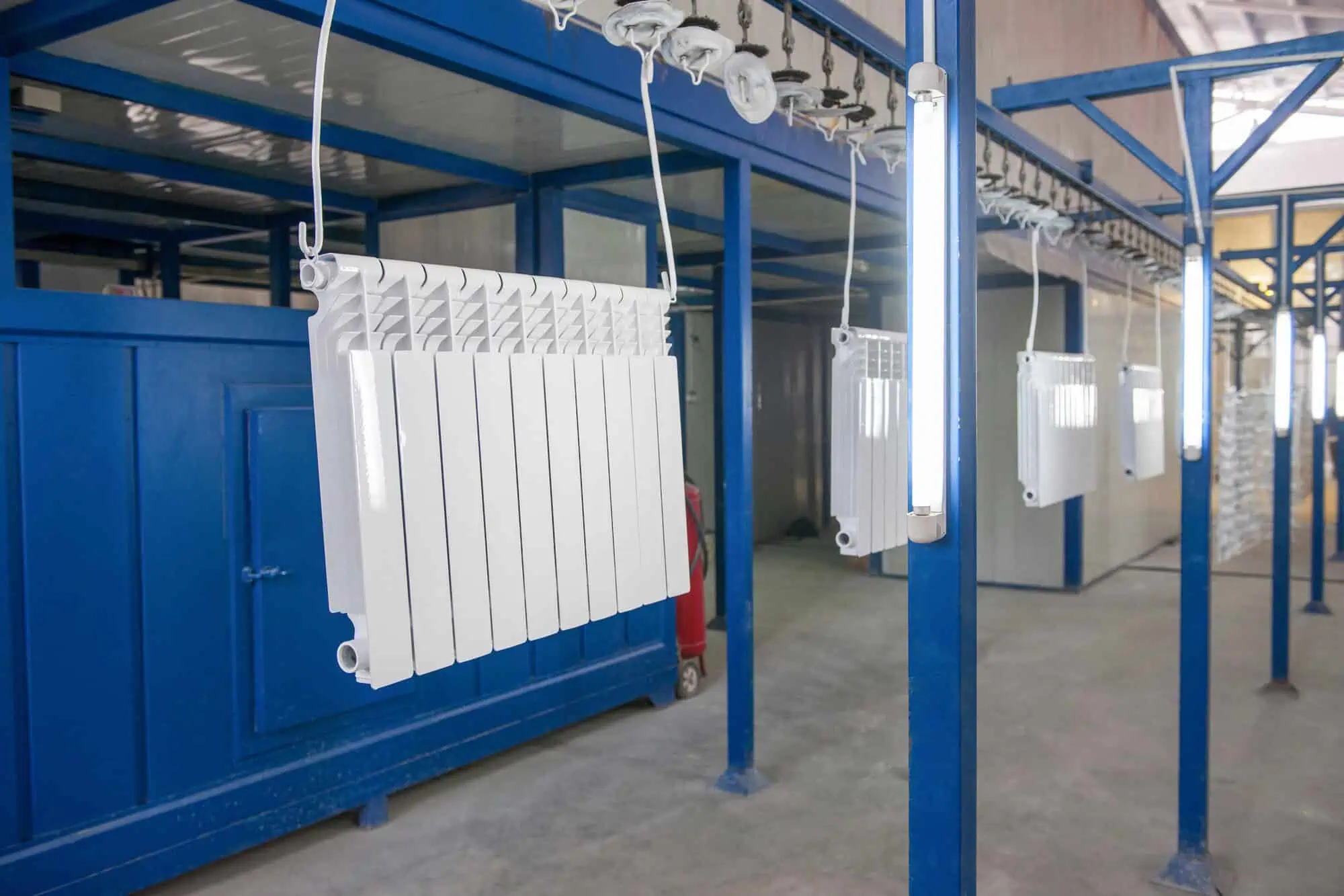 Radiators undergoing heavy-duty chemical stripping for rust removal in a production facility.