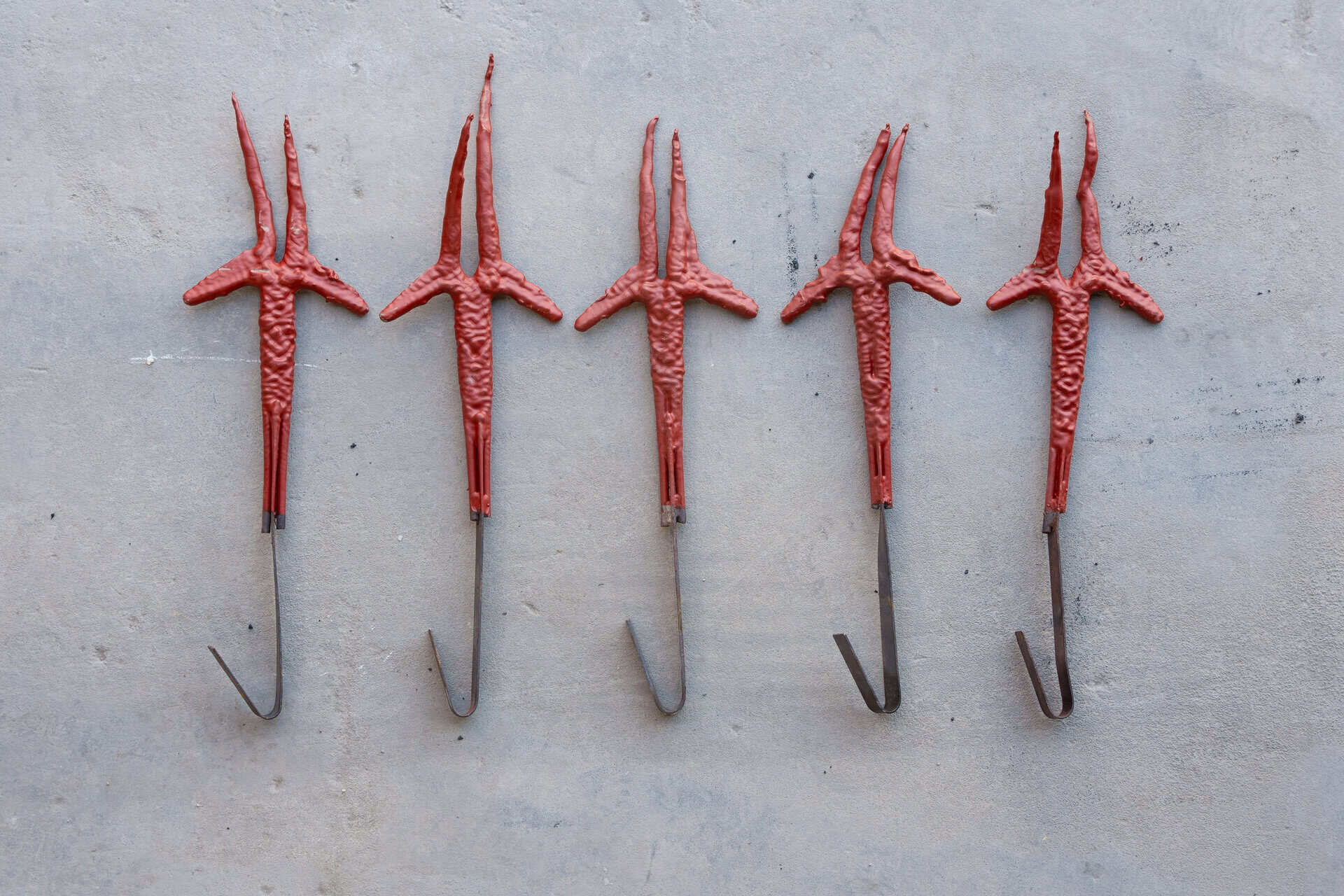 Five metal hooks coated in red paint, used for paint line fixtures, showcasing high-capacity paint removal.