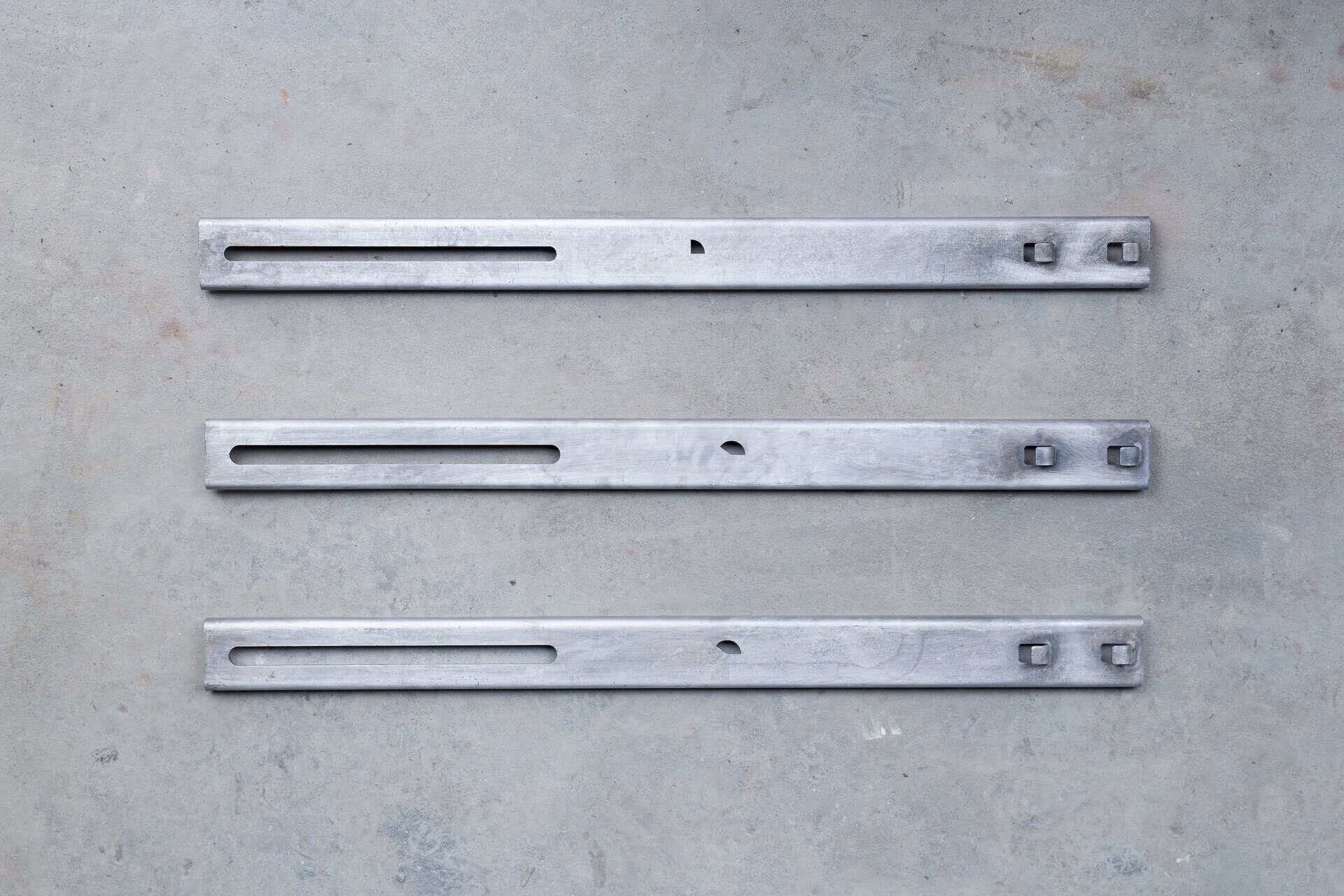 Three metal strips laid on a concrete surface, showcasing Carolina Chem Strip's capacity solutions for smooth, efficient production.