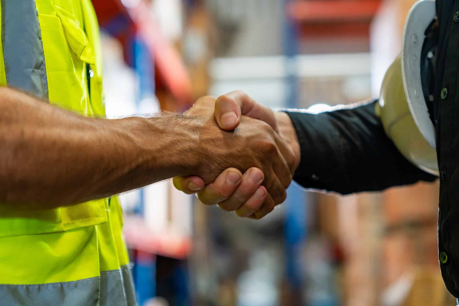 Handshake between two men in work attire, symbolizing agreement on rust removal and chemical stripping services.